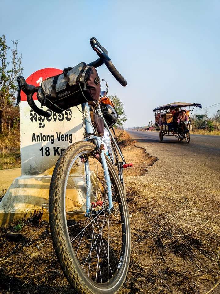 Bicycle leaning on a road marker 18 Km from Anlong Veng, Cambodia.