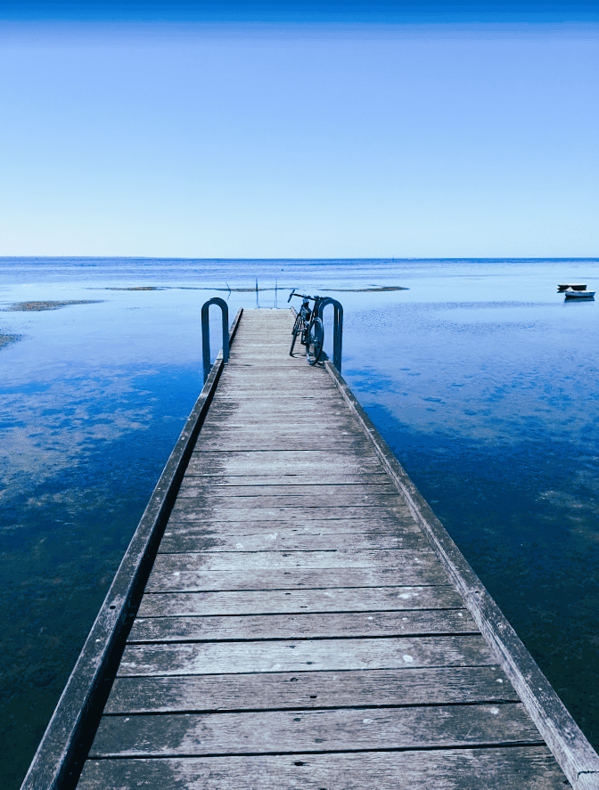 A single track pier going into wide open sea.