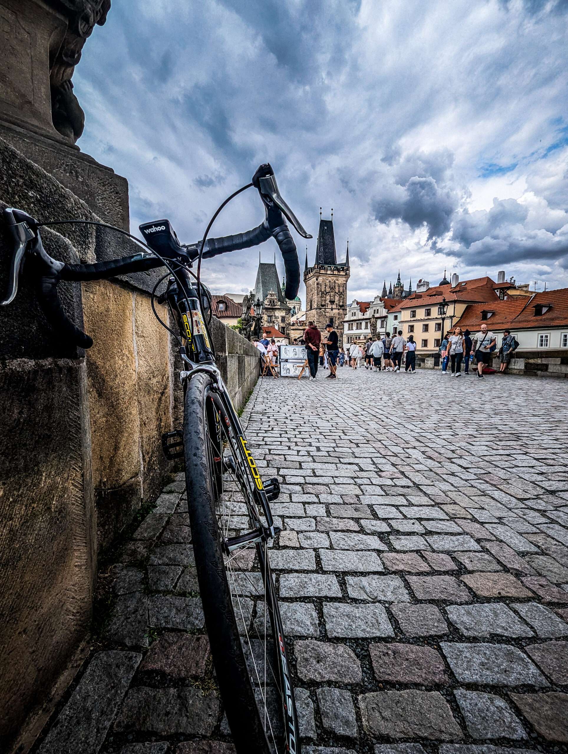 Charles Bridge beneath the wheels, the Lesser Town Bridge Tower rising ahead, and Prague Castle watching from the heights.