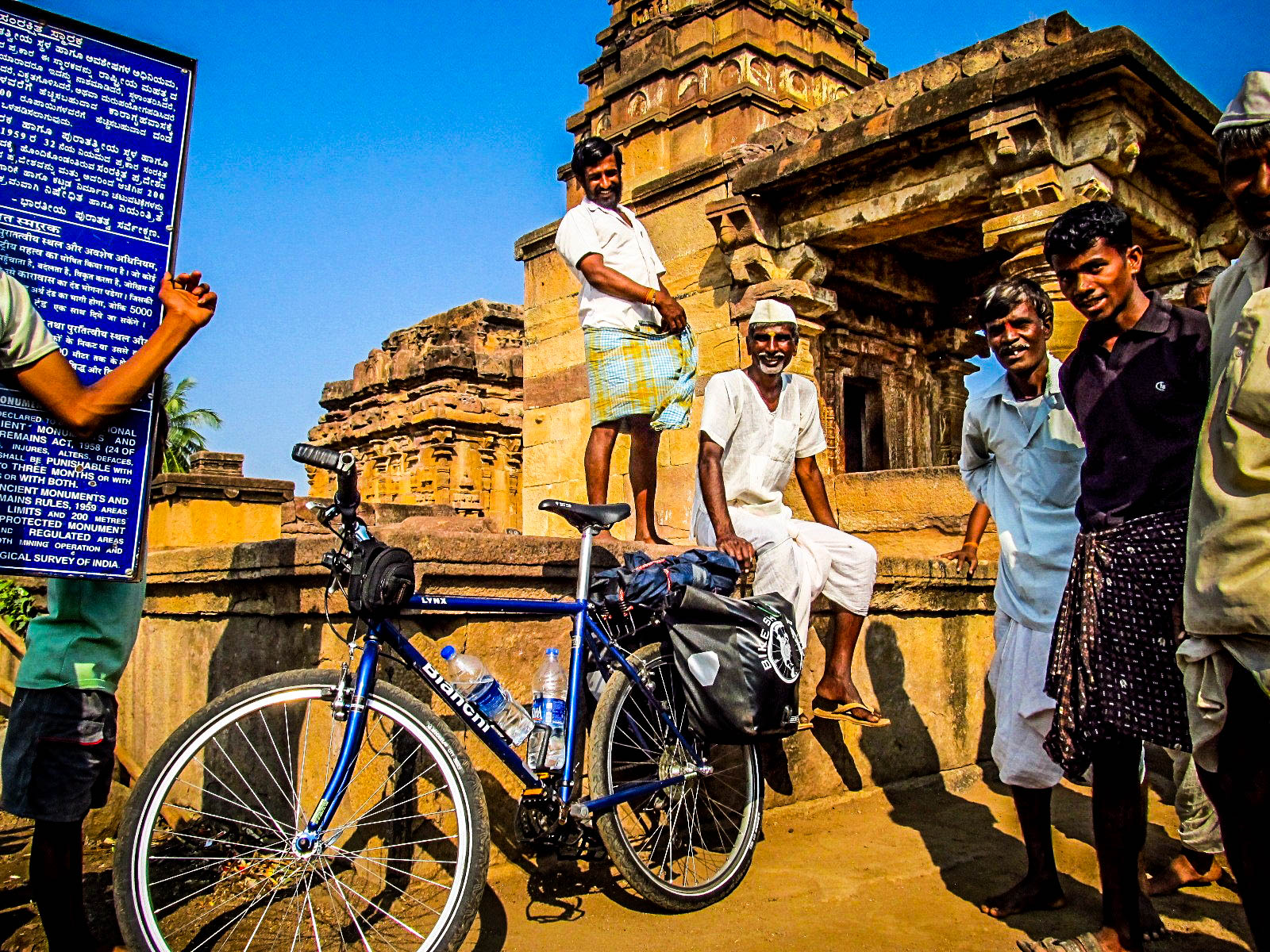 Fully loaded Bianchi touring bicycle admired closely by locals in front of an ancient temple.